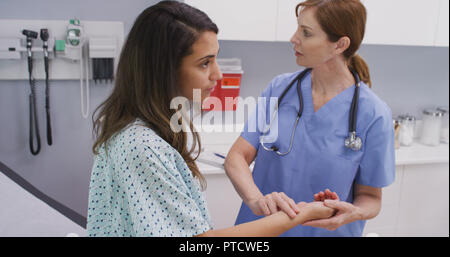 Medical nurse checking pulse of young patient indoors medical clinic Stock Photo