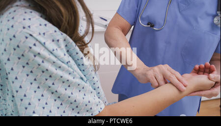 Medical nurse checking pulse of young patient indoors medical clinic Stock Photo