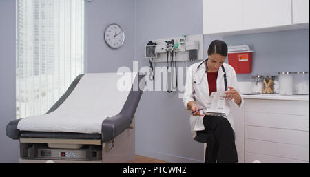 Close up of lovely latina doctor reviewing patients file indoors medical clinic Stock Photo