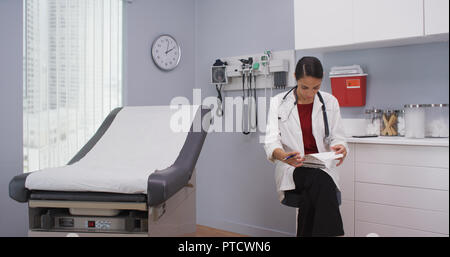 Close up of lovely latina doctor reviewing patients file indoors medical clinic Stock Photo