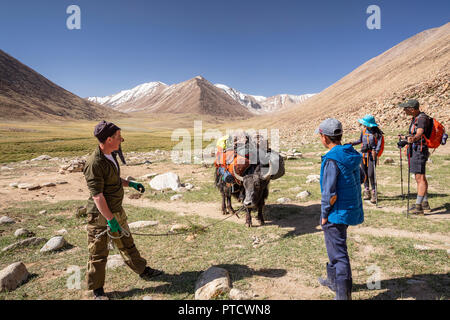 Kyrgyz herders and trekke in Keng Shiber with packed yak for trek to Bel Airyk Pass and Kara Jilga, Pamir Mountains, Gorno-Badakhshan, Tajikistan. Stock Photo