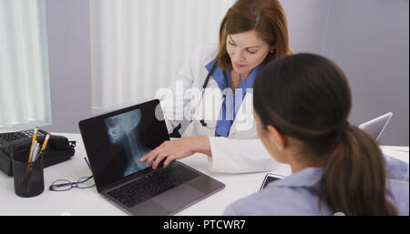 Close up of lovely latina patient viewing spinal x ray with doctor on latop Stock Photo