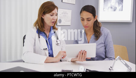 Senior medical physician using tablet to share lab results with young patient Stock Photo