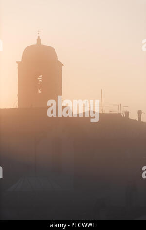 Chiusi mist fog sunrise of famous Cathedral Church bell tower in Umbria, Italy near tuscany, with warm sepia soft orange golden yellow pink brown vint Stock Photo