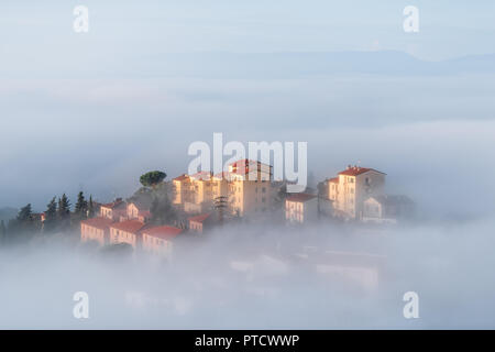Chiusi Scalo mist fog sunrise of rooftop houses buildings in Umbria, Italy near Tuscany, with soft clouds covering blanketing town, cityscape, haze Stock Photo
