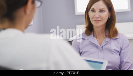 Close up of lovely senior patient talking with young female medical doctor Stock Photo