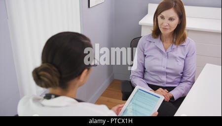 Lovely middle aged woman having chat with young medical doctor about health plan Stock Photo