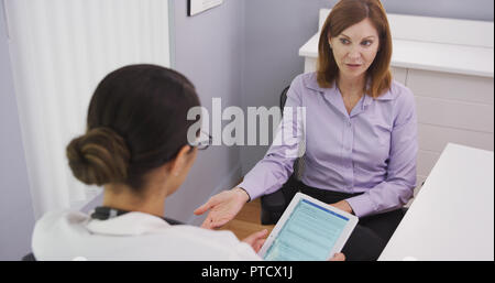 Lovely middle aged woman having chat with young medical doctor about health plan Stock Photo