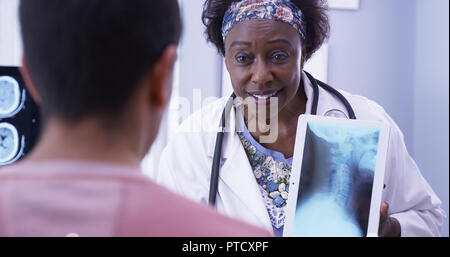 Kind senior medical doctor explaining to young male patient his neck xray Stock Photo