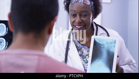 Kind senior medical doctor explaining to young male patient his neck xray Stock Photo