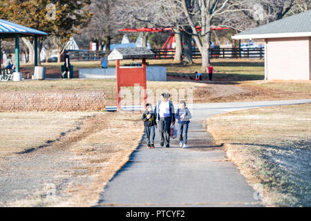 Reston, USA - February 15, 2018: A family of three, mother, mom with two sons, boys walking on path, trail near Lake Fairfax with children playground, Stock Photo