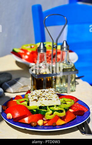 Greek salad with sheep cheese served on plate, vinegar and oil on the back, Greek tavern, mirtos, crete, Greece Stock Photo