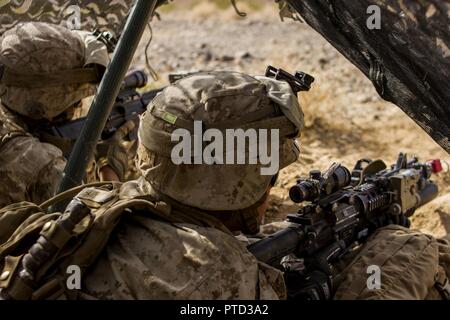 Lance Cpl. Martin Flores Blanks and Lance Cpl. Preston Haigh, both riflemen with 2nd Battalion, 7th Marines Regiment, 1st Marine Division, hold a defensive position in a fighting hole during a Marine Corps Combat Readiness Evaluation (MCCRE) at Marine Air Ground Combat Center Twentynine Palms, Calif., July 8, 2017. The 2/7 MCCRE is in preparation for the upcoming deployment with the Special Purpose Marine Air Ground Task Force. Stock Photo