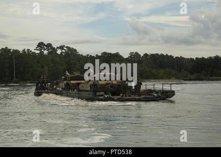 Marines begin crossing a river on a seven-bay raft system with two M1A1 Abrams tanks during exercise Iron Wolf at Camp Lejeune, N.C., July 10, 2017. Exercise Iron Wolf is one of the largest exercises conducted this year at Camp Lejeune, integrating 16 different units from II Marine Expeditionary Force to train for realistic scenarios. The Marines are with 8th Engineer Support Battalion and 2nd Tank Battalion. Stock Photo