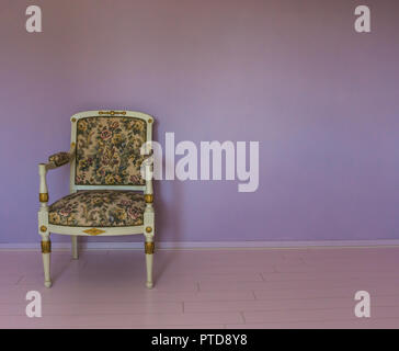 empty white armchair standing in a empty room with pink laminate and purple stone wall background Stock Photo