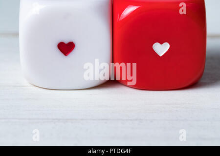 Two red and white Valentines Day heart dice on wooden background. Copy space on the bottom. Stock Photo