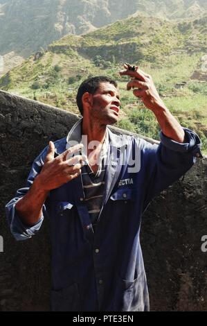 Santo Antao Island, Cape Verde - Jan 5 2016: local farmer having a rest under the sun in front of a stone fence and beautiful desert arid mountain bac Stock Photo