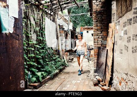 Beijing / China - JUN 24 2011: man cleaning the street outside of his home in a typical city hutong Stock Photo