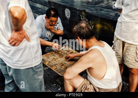 Beijing / China - JUN 24 2011: people playing typical xiangqi chinese chess on the street in a traditional chinese city hutong