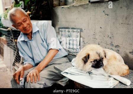 Beijing / China - JUN 24 2011: two man playing with a dog outside their home in a traditional chinese city hutong