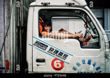 Beijing / China - JUN 24 2011: young boy waiting in the cabin of a lorry