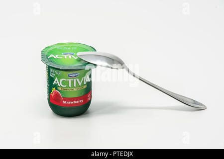 Portland, OR / USA - October 8 2018: Activia Dannon probiotic yougurt in a green plastic cup with a metal spoon on top of it. Stock Photo