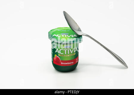 Portland, OR / USA - October 8 2018: Activia Dannon probiotic yougurt in a green plastic cup with a metal spoon on top of it. Stock Photo