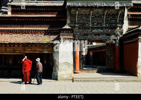 Labrang Monastery, Xiahe, Gansu Province / China - JUN 6 2011: a tibetan monk is talking with a pilgrim man in front of the temple with outstanding de Stock Photo