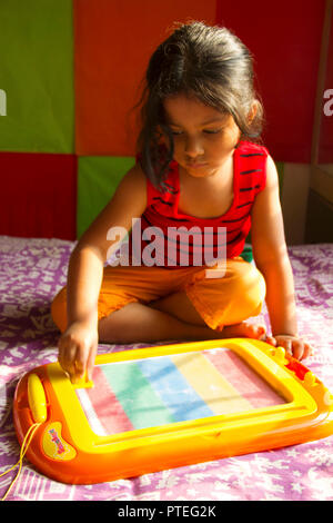 Little girl playing with magnetic drawing board, Pune, India Stock Photo