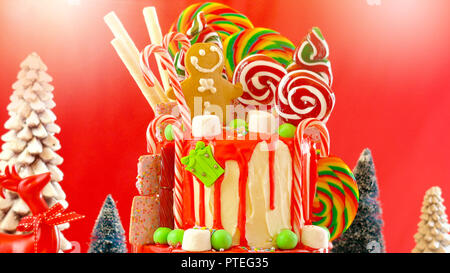 On trend festive candyland Christmas drip cake on red background. Stock Photo