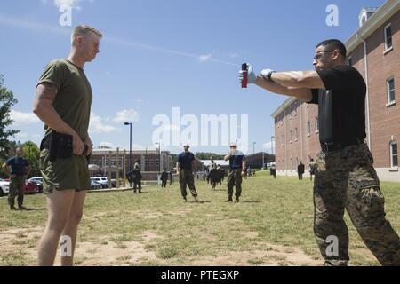 U.S. Marine Corps Gunnery Sgt. Louis H. Flores, right, instructor advisor with Marine Corps Embassy Security Group sprays a student during oleoresin capsicum (OC) spray training on Marine Corps Base Quantico, Va., July 7, 2017. Students are sprayed with OC as a part of their training to become Marine Security Guards. Stock Photo