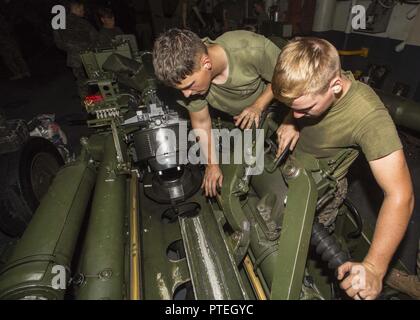 Sgt. Joshua Mellen (left) gives Lance Cpl. Joshua Brooks (right) guidance on cleaning the M777A2 Howitzer aboard USS Iwo Jima (LHD 7) during Amphibious Squadron – Marine Expeditionary Unit Integration Training (PMINT) off the coast of Onslow Beach, N.C., July 12, 2017. PMINT allows the Navy-Marine Corps team to improve interoperability and exercise the unique capabilities of the Amphibious Task Force.  Mellen and Brooks are field artillery cannoneers with Battalion Landing Team 2/6, 26th Marine Expeditionary Unit.