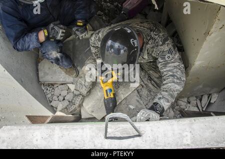 Two Airmen use hammer drills and heavy duty saws to make a hole in a concrete wall during a simulated search and rescue exercise at Volk Field, Wis. July 18, 2017. The PATRIOT North exercise is a Domestic Operations disaster-response training exercise conducted by National Guard units working with federal, state and local emergency management agencies and first responders. Stock Photo