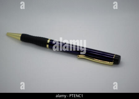 blue and black pen with gold trim on off white background Stock Photo