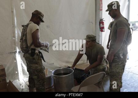 Spc. Jevon Salmon, from Stratford, Connecticut., with the Forward Support Company, 192nd Engineer Battalion, Connecticut Army National Guard, mixes tea with Pvt. Alexis Galvez, from Cochella Valley, California., with C Company, 1st Battalion, 60th Infantry Regiment, California Army National Guard, Pfc. Joshua Rosa Nieves, from Toa Baja, Puerto Rico, at the dining facility on Forward Operating Base Warrior at the Joint Readiness Training Center on Fort Polk, Louisiana, Tuesday, July 18, 2017. The soldiers were assigned to the 76th Infantry Brigade Combat Team, 38th Infantry Division, Indiana Ar Stock Photo