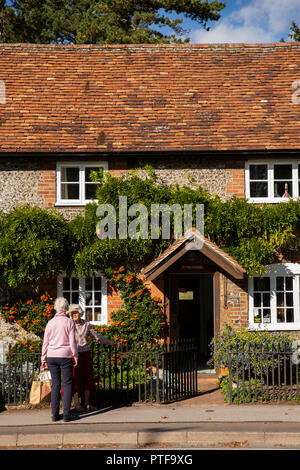 England, Berkshire, Goring on Thames, High Street, women chatting outside idyllic, traditionally built Bridge Cottage with small front garden Stock Photo