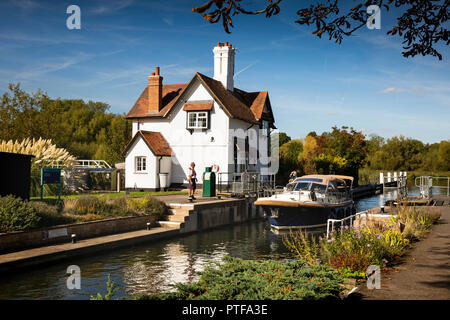England, Berkshire, Goring on Thames, lock keepers cottage at locks on River Thames as expensive cabin cruiser enters lock Stock Photo