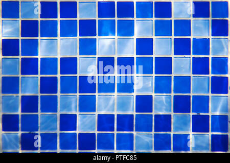 Square pattern of blue and light blue tiles for bath walls and floor design or swimming pool design. Water blinks on tiled walls in a water park. Indo Stock Photo