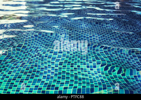 A fish eye effect of indoor pool rippling water at the blue-tiled mosaic floor. Waving of clean water in swimming pool with tiled floor. Swinging of w Stock Photo