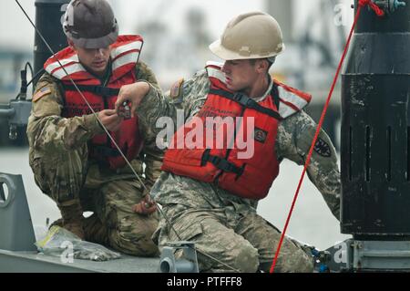 Pfc. Zach Figueroa, a member of the 331st Transportation Company, takes a bolt from Pvt. Michael Grella, also with the 331st, while reassembling a modular warping tug in the Port of San Diego during training on July 16, 2017, in support of an engineering project to construct a causeway. The causeway is used to quickly move supplies from ships to shore. U.S. Army Reserve Command Soldiers are participating in Exercise Big LOTS West, a joint military training exercise designed to reinforce the 1394th Transportation Brigade's ability to rapidly deploy vital combat equipment to an operational envir Stock Photo