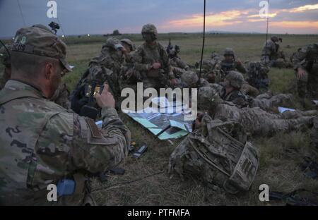 A U.S. Soldier, left, of the Timberwolf Team, Joint Multinational Readiness Center (JMRC) (Operations Group) takes a photo of paratroopers of the 173rd Airborne Brigade while conducting a joint force entry during Exercise Saber Guardian at the Bezmer Training Area, Bezmer, Bulgaria July 18, 2017. Saber Guardian 2017 is a multinational military exercise involving approximately 25,000 military personnel from 23 participating nations. The exercise is part of U.S. European Command's Joint Exercise Program designed to enhance joint combined interoperability between Bulgarian, Romanian, Hungarian, U Stock Photo