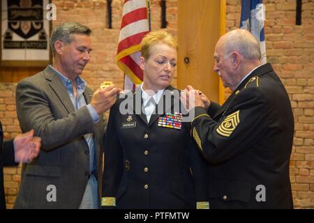 Louisiana National Guard Maj. Gen. Joanne F. Sheridan’s husband and father remove her old rank and replace it with the new rank of Maj. Gen at the Ansel M. Stroud Military History & Weapons Museum at Jackson Barracks in New Orleans, Louisiana, July 21, 2017. In her new role as the assistant adjutant general, she now serves as a principal advisor to the adjutant general. She is responsible for assisting the adjutant general in the deployment and coordination of programs, policies, and plans for the LANG. Stock Photo