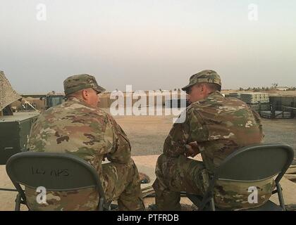 U.S. Air Force Master Sgts. Daniel and Scott Hose, both assigned to the 370th Air Expeditionary Advisory Group, catch up with one another at Qayyarah West Airfield, Iraq, July 13, 2017. The twin brothers are both deployed to Iraq in support of Combined Joint Task Force -Operation Inherent Resolve. CJTF-OIR is the global Coalition to defeat ISIS in Iraq and Syria. Stock Photo