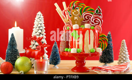 On trend festive candyland Christmas drip cake on red background. Stock Photo