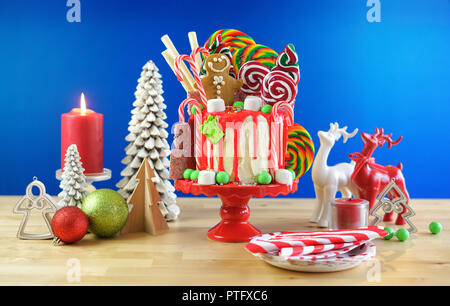 On trend festive candyland Christmas drip cake on blue background. Stock Photo