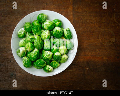 Photo of a bowl of uncooked brussels sprouts on old wood table. Stock Photo