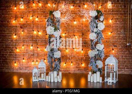 Coniferous branches with hydrangea bushes, candles and light bulbs on a brick background Stock Photo