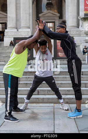 STREET PERFORMERS. A team of acrobatic breakdancing buskers huddle in front of the main branch of the NY Public Library on Fifth Ave. in Manhattan. Stock Photo