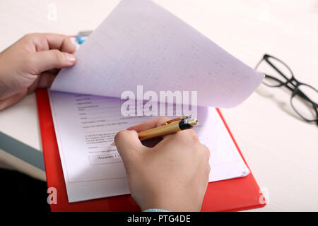 Man signature on the form with pen. Picture of glasses and clipboard on the table. Stock Photo