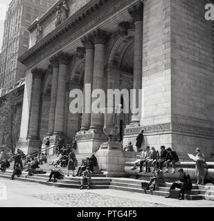 1960s, historical, people sitting on the steps at the imposing marble columned entrance to the New York public library (main building) in midtown Manhattan, New York city, New York, USA. Stock Photo